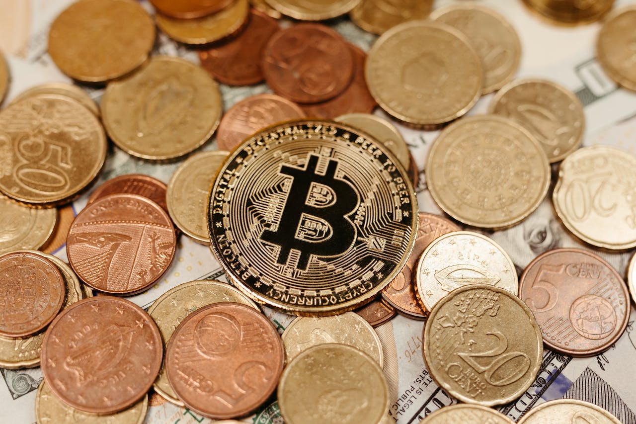 A Bitcoin coin lies on top of various euro and dollar coins, symbolizing digital currency and financial diversity.